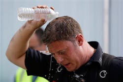 Jersey City firefighter Corey Keeper pours water on himself after firefighters battled a four-alarm fire, Friday, July 19, 2013, in Jersey City, N.J.
