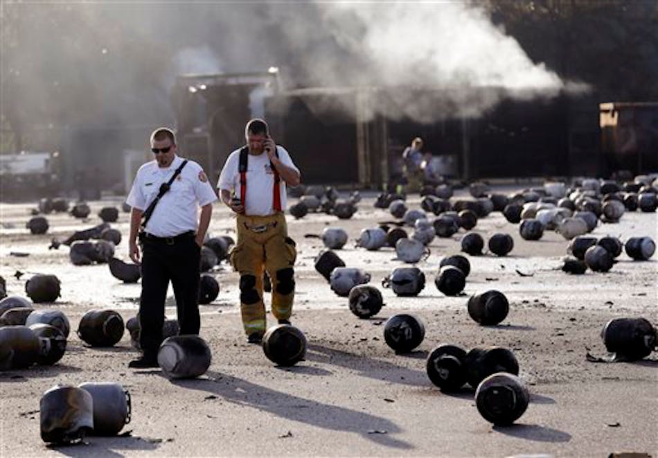Firefighters walk through the blast site littered with tanks.