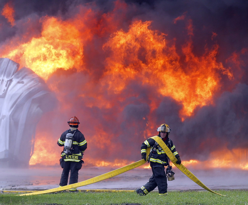 Firefighters haul hose to hit blaze at Sedgwick Green Products Plant.