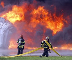 Firefighters haul hose to hit blaze at Sedgwick Green Products Plant.