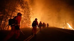 Inmate firefighters walk along state Highway 120 as firefighters continue to battle the Rim Fire near Yosemite National Park, Calif., on Sunday, Aug. 25, 2013. Fire crews are clearing brush and setting sprinklers to protect two groves of giant sequoias as a massive week-old wildfire rages along the remote northwest edge of Yosemite National Park. AP Photo/Jae C. Hong