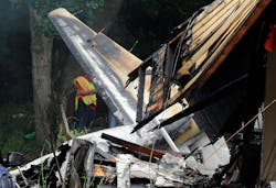 A firefighter examines the wreckage of a plane that crashed into houses.