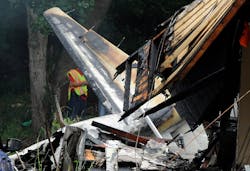 A firefighter examines the wreckage of a plane that crashed into houses. A firefighter examines the wreckage of a plane that crashed into houses.