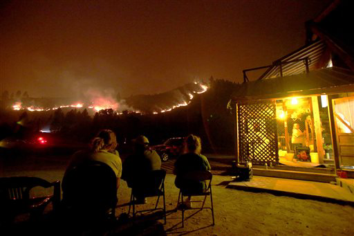 Residents sit and watch the wildfire burning on an adjacent hill, saying they're staying planted.