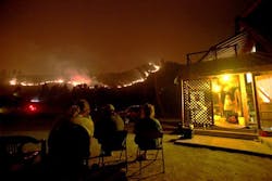 Residents sit and watch the wildfire burning on an adjacent hill, saying they're staying planted. Residents sit and watch the wildfire burning on an adjacent hill, saying they're staying planted.