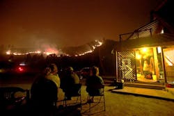 Residents sit and watch the wildfire burning on an adjacent hill, saying they&apos;re staying planted.