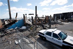A Seaside Park police officer sits in his cruiser near the charred rubble in Seaside Park, N.J., Tuesday, Sept. 17, 2013, after a fire last Thursday that started near a frozen custard stand in Seaside Park, quickly spread north into neighboring Seaside Heights. More than 50 businesses in the two towns were destroyed. The massive boardwalk fire in New Jersey began accidentally, the result of an electrical problem, an official briefed on the investigation said Tuesday.
