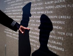 A firefighter touches the name of a fallen hero on the Canadian Fallen Firefighter Memorial.