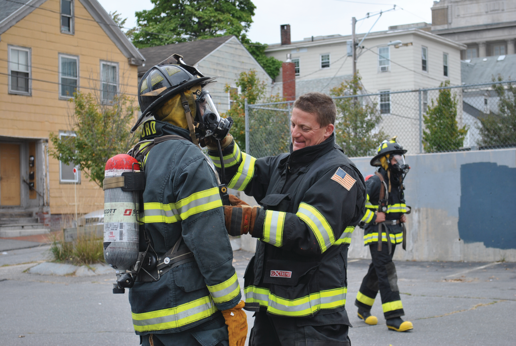 A Portland Fire Department instructor teaches a high school student to properly don self-contained breathing apparatus (SCBA) during the 'Introduction to Firefighting Fundamentals' course.