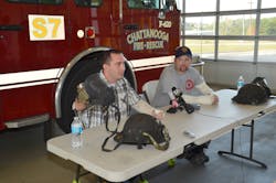 Senior Firefighter Dan Peterson (left) shows the charred face mask he was wearing inside the fire as Firefighter Chad Williams watches.