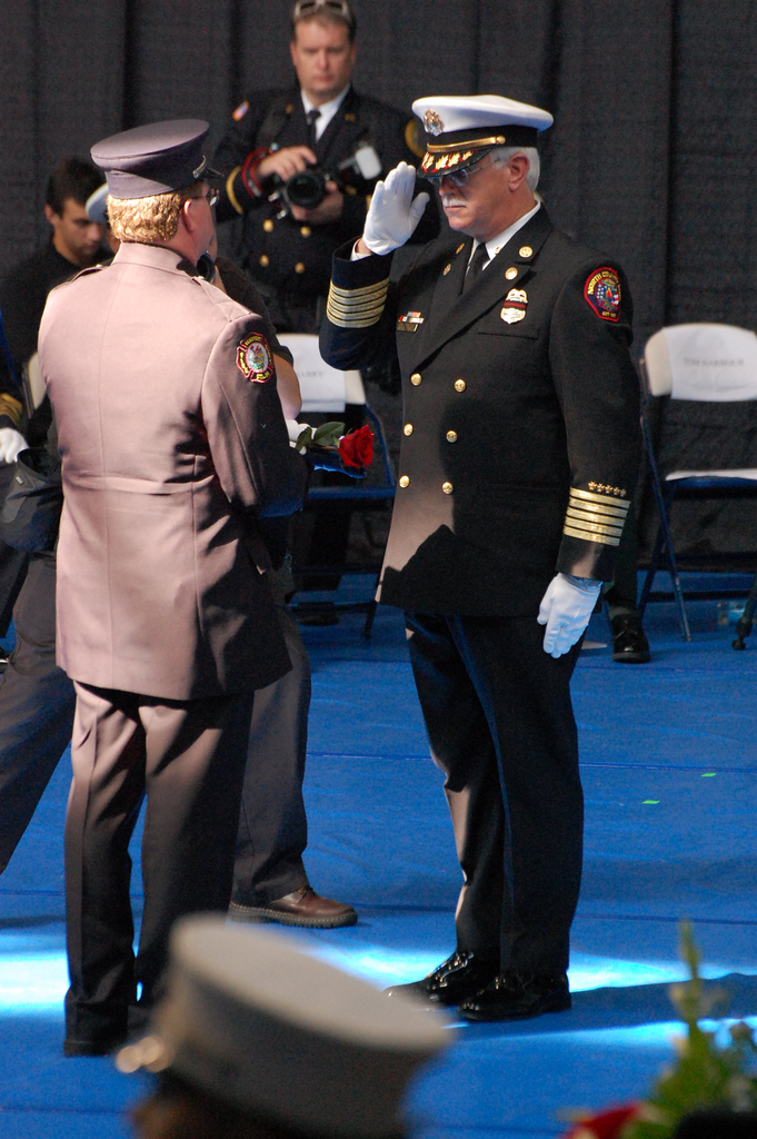 A flag and rose are handed to a presenter that would be handed to the family of a fallen firefighter.