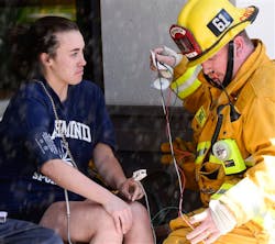 A Los Angeles City Fire Department firefighter examines Margaret Kurtz, of Washington, Friday, Oct. 4, 2013, in Los Angeles. Flames fully engulfed an apartment on the 11th floor around noon in the Brentwood section of the city. Kurtz was visiting a friend on the 23rd floor when the fire broke out.