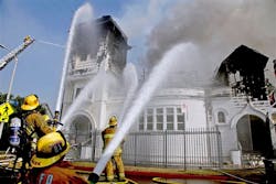 LA firefighters train hoses on a church fire on Tuesday.