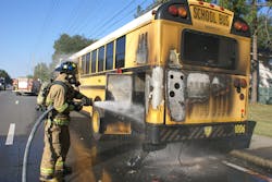 A firefighter applies water to the burning bus in Ocala Friday.