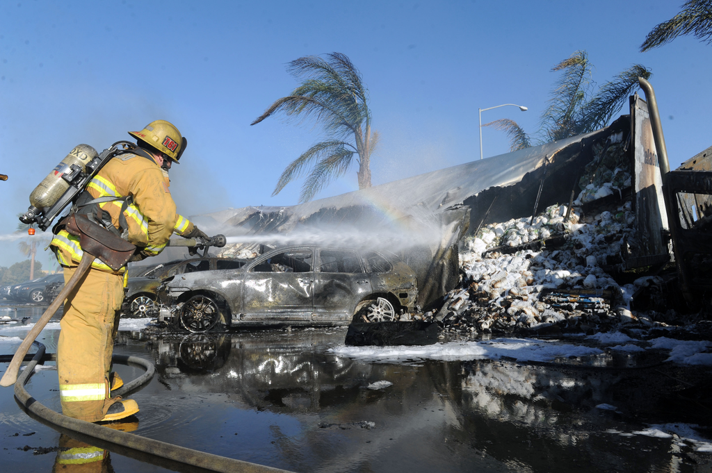 A firefighters sprays water after a semi crashed on the 101 freeway south near Rose Avenue, Saturday, Oct. 5, 2013 in Oxnard, Calif.