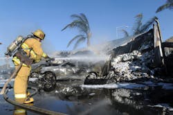 A firefighters sprays water after a semi crashed on the 101 freeway south near Rose Avenue, Saturday, Oct. 5, 2013 in Oxnard, Calif.