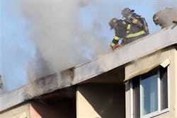 Firefighters open the roof of an apartment building. Firefighters open the roof of an apartment building.