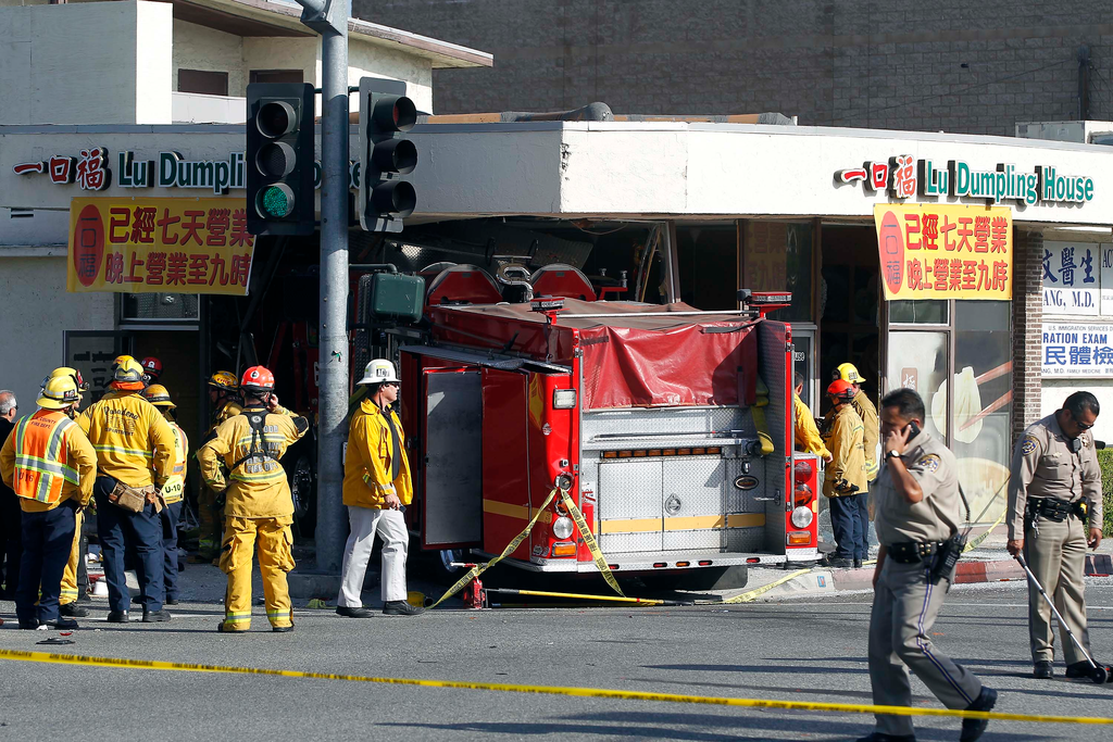 Firefighters and other officials work the scene of an accident where two firetrucks answering a call collided en route to a fire Wednesday, April 16, 2014, in Monterrey Park, Calif. The collision sent one firetruck careening into a restaurant, leaving 14 people, including several firefighters, injured.