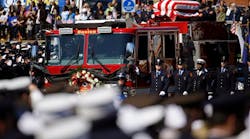 The casket of Firefighter Michael Kennedy moves through the street.