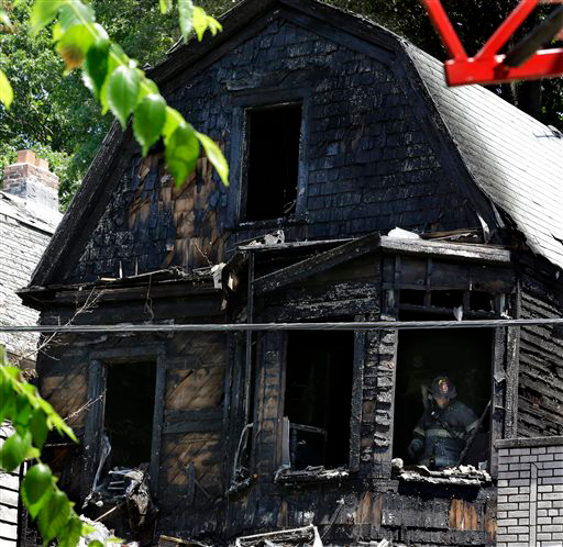 Firefighters pick through the rubble of a burned out home as they look for clues to a fire that authrities say killed six people in Newark, N.J., Sunday, June 15, 2014. The Essex County prosecutor's office says the fast-moving fire that roared through a single-family home in New Jersey's largest city, broke out at around 4 a.m. Sunday.