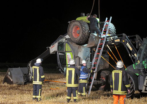 In this picture taken late Tuesday, July 29, 2014, firefighters try to set up a mechanical digger on a field near Isselburg, western Germany. German authorities say a man was killed and several others were injured when the digger tipped over and hit them during a so-called Cod Water Challenge.