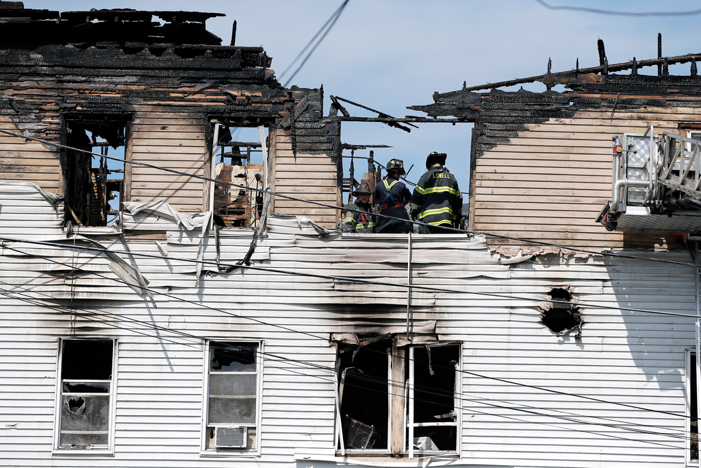 Firefighters work on the top floor inside a burned three-story apartment and business building in Lowell, Mass., Thursday, July 10, 2014, where officials said seven people died in a fast-moving pre-dawn fire.