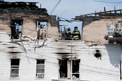 Firefighters work on the top floor inside a burned three-story apartment and business building in Lowell, Mass., Thursday, July 10, 2014, where officials said seven people died in a fast-moving pre-dawn fire.
