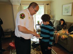 Fire Chief Jerome LaMoria presents Nicholas Burnham with a Portland Fire Department challenge coin for his actions after his grandmother suffered a medical emergency at home.