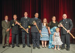 The Firehouse&circledR; Magazine Heroism Awards program honored members of the Bryan, TX, Fire Department during the Opening Ceremonies at Firehouse Expo 2014 in Baltimore, MD, in July. From left to right: Bryan City Manager Kean Register; Assistant Chief Terry Barnett; Fire Chief Randy McGregor; Firefighter Mitchel Moran and his fiancee, Katy Garcia; Kara Mantey and Kanzie Mantey, wife and daughter of Firefighter Ricky Mantey; and Mantey. Lieutenant Greg Pickard was honored posthumously.