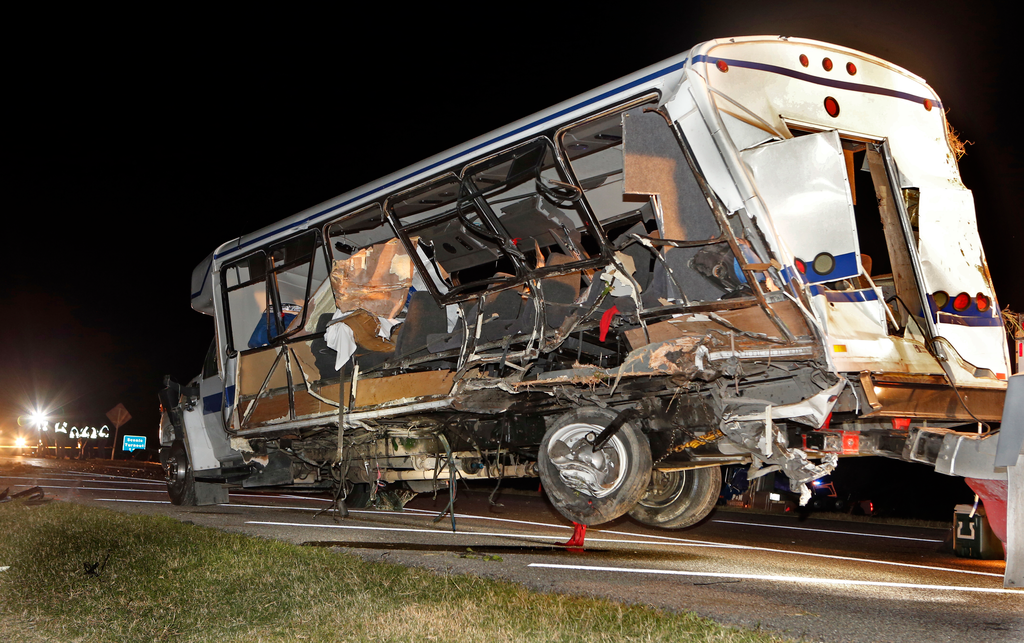 A wrecker removes the team bus as Highway Patrol and emergency personnel work the scene of a fatality accident just south of the Turner Falls area.on Saturday, Sept. 27, 2014 in Davis, Okla. Four members of a Texas college softball team died after a tractor trailer crossed over the center median on Interstate 35 and collided with the team's bus Friday night.