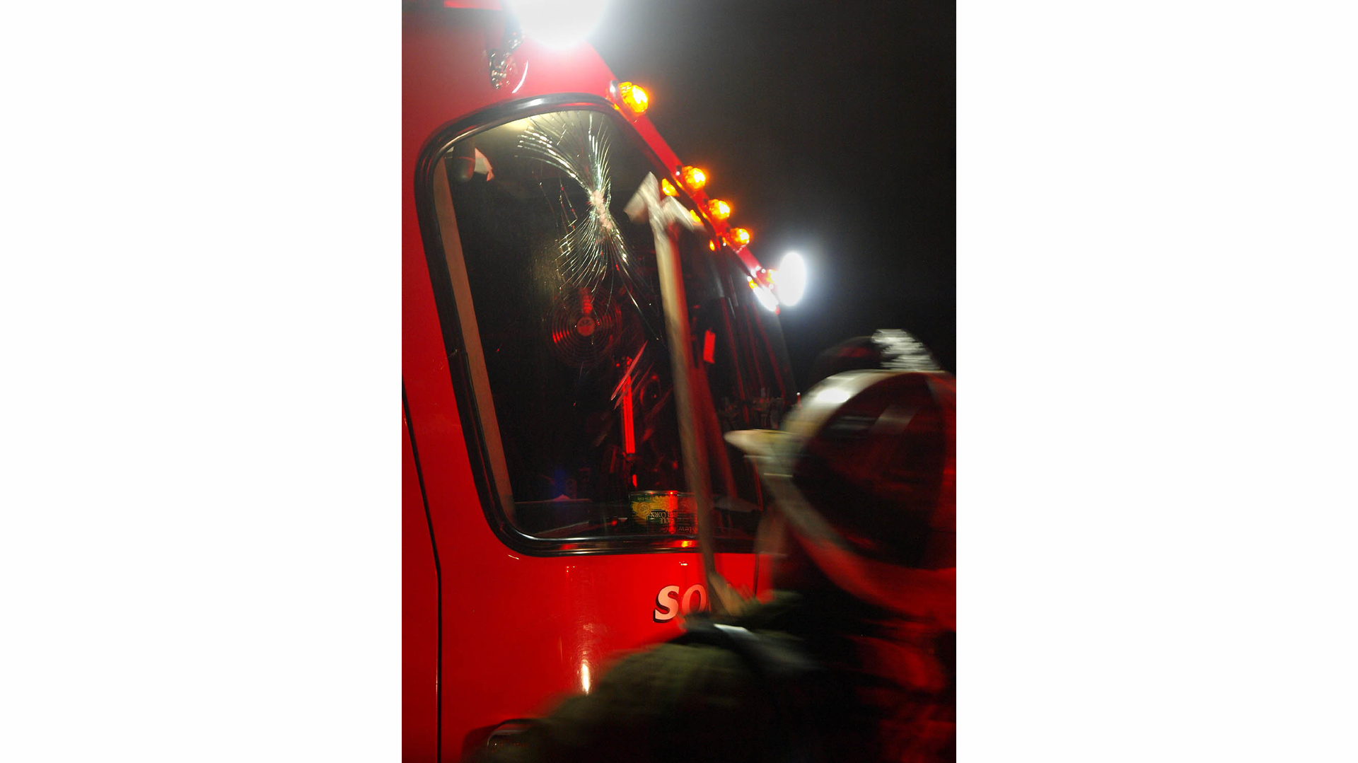 A Detroit firefighter looks at the damaged windshield of Squad 3. Had the brick fallen a second later, the officer may have been seriously injured.