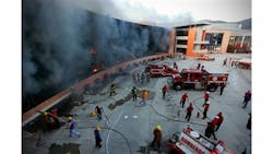 Firefighters try to extinguish the flames after the state capital building was set on fire by protesting college students in Chilpancingo, Mexico, Monday Oct. 13, 2014.