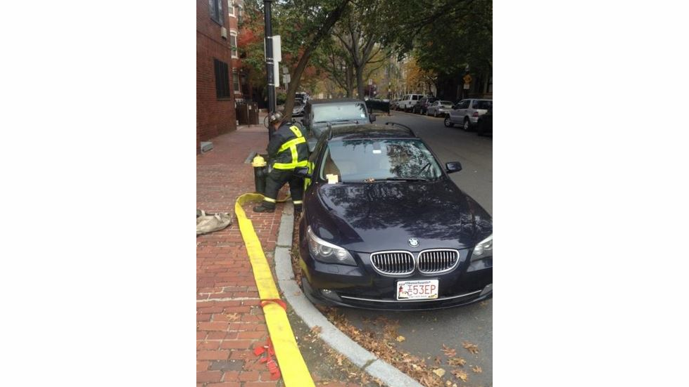 A Boston firefighter tries to hook up to a a hydrant that is blocked by an illegally parked car.