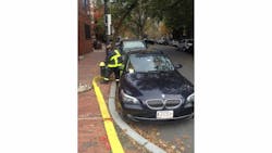 A Boston firefighter tries to hook up to a a hydrant that is blocked by an illegally parked car.