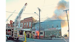 Ovid and Trumansburg quints set up for ladder pipe operations as fire is showing from the tax assessor’s office on side A. Ovid and Trumansburg quints set up for ladder pipe operations as fire is showing from the tax assessor’s office on side A.