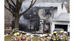Firefighters gather outside one of the homes destroyed after a plane crash. Firefighters gather outside one of the homes destroyed after a plane crash.