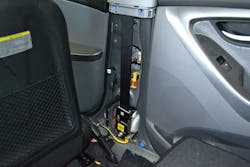 With the inner trim removed, the entire seatbelt pretensioner system on this 2012 Hyundai Elantra is visible. This is a recoiler-type unit that rewinds the seatbelt webbing when activated by a collision.