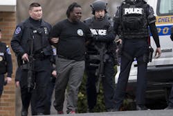 Police escort a man away from a firehouse, Tuesday, March 31, 2015, in Elkins Park, Pa. Police SWAT team members converged on the Philadelphia-area firehouse after a call about an armed man and a report of hostages.