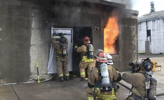 Truck company firefighters hang a smoke blocker and while a hose crew prepares to assess conditions with hoseline and thermal imagine camera.