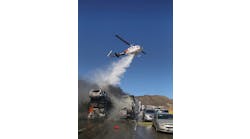 Helicopters drop water to douse burning vehicles.