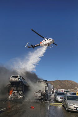 Helicopters drop water to douse burning vehicles.