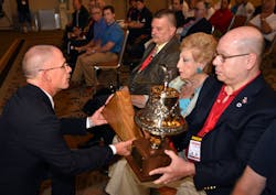 Firehouse Editor-in-Chief Tim Sendelbach presents a memorial bell and American Flag to Harvey Eisner's brother Carey, right, and mother Carol. Firehouse Editor-in-Chief Tim Sendelbach presents a memorial bell and American Flag to Harvey Eisner's brother Carey, right, and mother Carol.