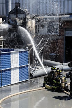 Prior to the collapse of the ductwork, firefighters operate a 2-1/2&apos; hoseline off first-due Engine 967 to darken down the fire.