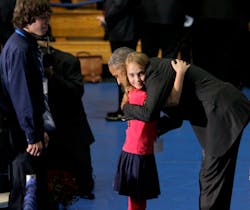 A little girl gets a hug from President Obama.