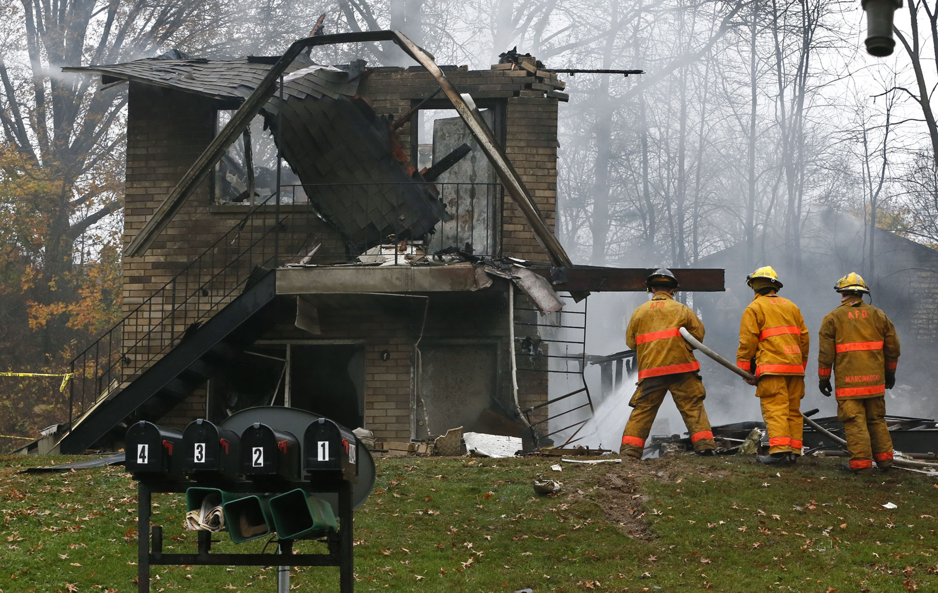 Area police and firefighters work at the scene after a passenger jet crashed into a home on Mogadore Road while on a short approach to Akron-Fulton Airport on Tuesday, Nov. 10, 2015, in Akron, Ohio.