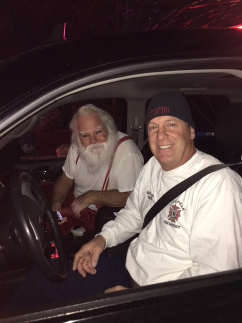 With his 'sleigh' destroyed by flames, Santa hitches a ride with a Lone Peak firefighter to continue his rounds.