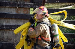 A firefighter hauls hose at the Lancaster fire scene. A firefighter hauls hose at the Lancaster fire scene.
