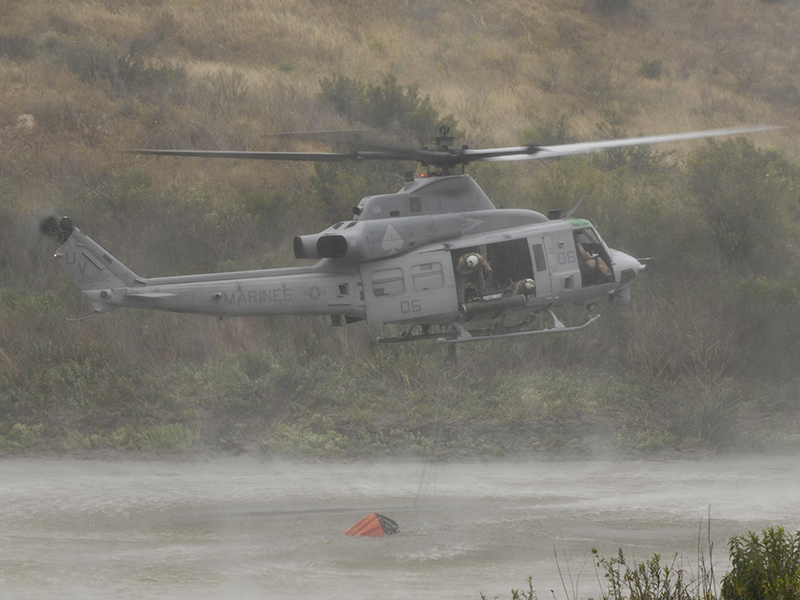 A Marine UH-1Y Venom fills up its Bambi Bucket from Lake Pulgas.
