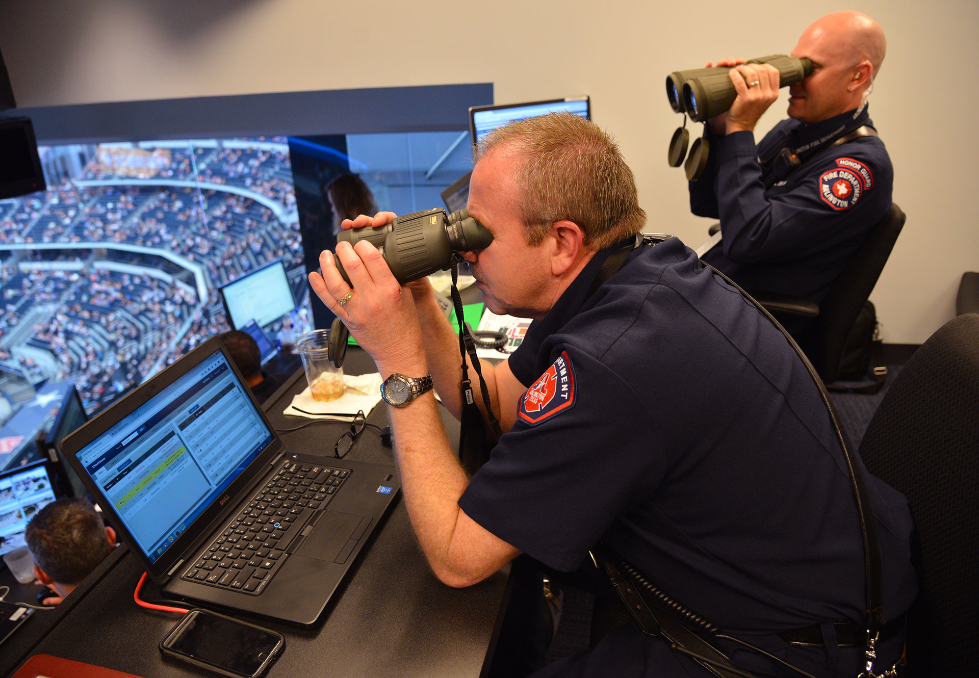 Battalion Chief Gerald Randall and firefighter Danny Martin use binoculars to assess a report of a person with a head injury on the floor.