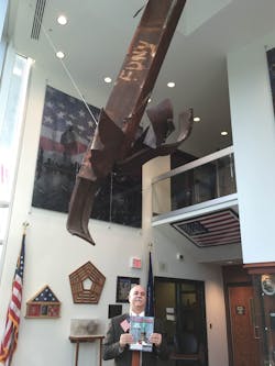 Charles Werner standing with a piece of 9/11 Memorial Steel, now suspended from the ceiling in CFD Station 10. He wrote about the trip to JFK Hangar 17 to take possession of the Memorial Steel in the September 2011 issue. Charles Werner standing with a piece of 9/11 Memorial Steel, now suspended from the ceiling in CFD Station 10. He wrote about the trip to JFK Hangar 17 to take possession of the Memorial Steel in the September 2011 issue.